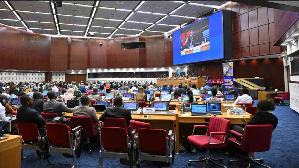 The Closing Session of the Africa Early Warnings Forum - many people are gathered, sitting down, in a conference hall. A large screen is shown in the background of the image, with a speaker's face projected onto it 