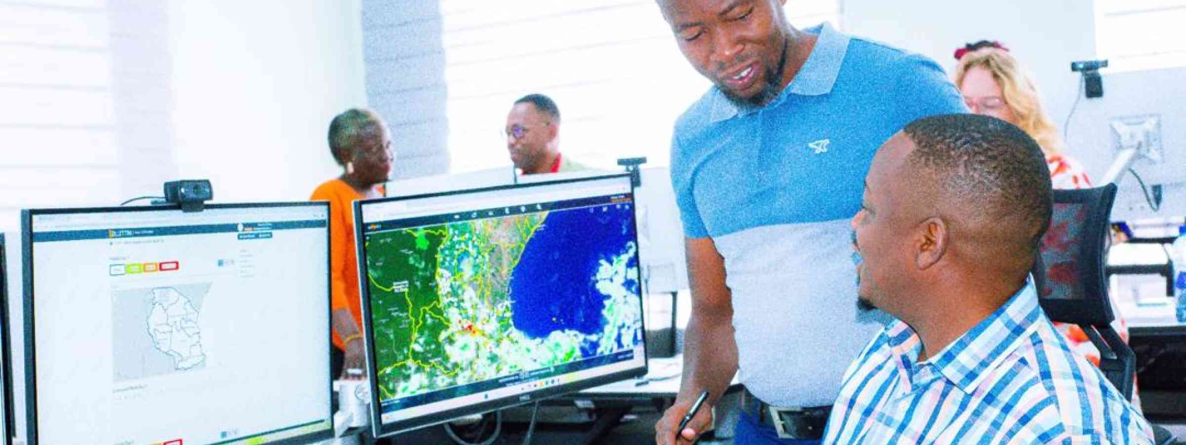 Two men talking in front of a computer in the Tanzanian Situation room
